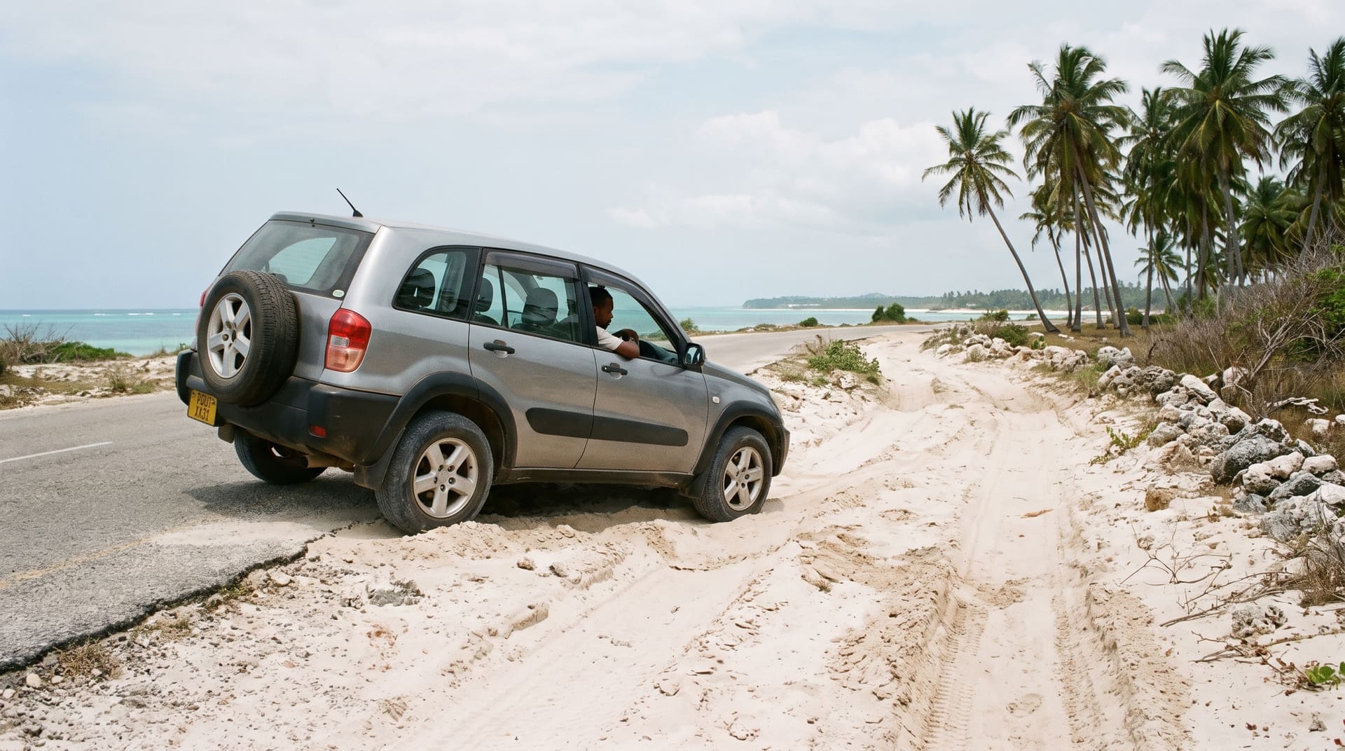 A silver Toyota RAV4 turning off the tarmac onto a sand access track by the coast